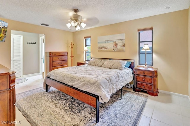 423 SE 17th St, Cape Coral, FL 33990 - bedroom with a textured ceiling, visible vents, baseboards, tile patterned floors, and a ceiling fan