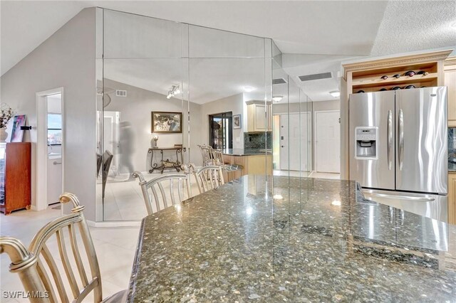 423 SE 17th St, Cape Coral, FL 33990 - kitchen with lofted ceiling, dark stone counters, visible vents, and stainless steel fridge
