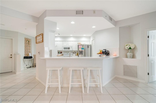 9150 Southmont Cv Unit 203, Fort Myers, FL 33908 - kitchen with visible vents, a breakfast bar, white microwave, and stainless steel refrigerator with ice dispenser