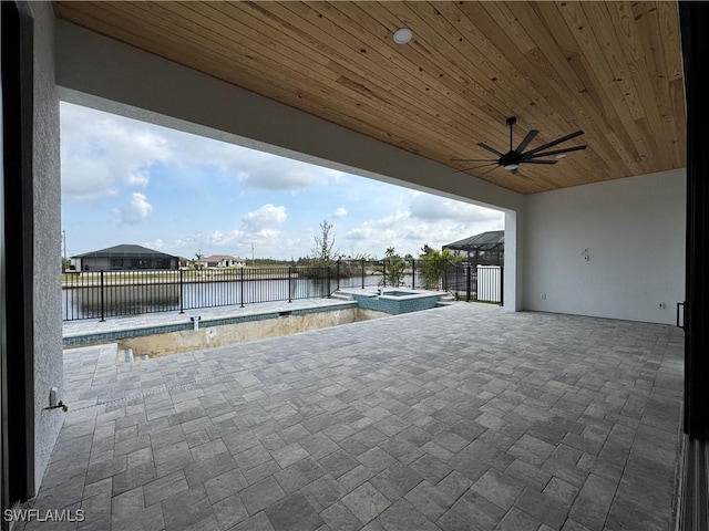 view of patio featuring a water view, a pool with connected hot tub, fence, and ceiling fan