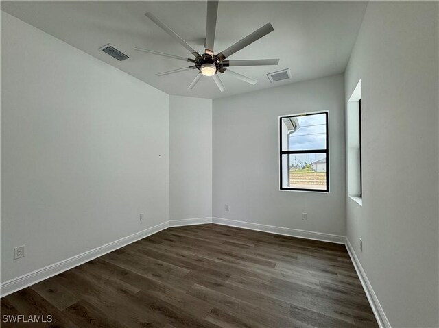 spare room featuring dark wood-type flooring, ceiling fan, and visible vents