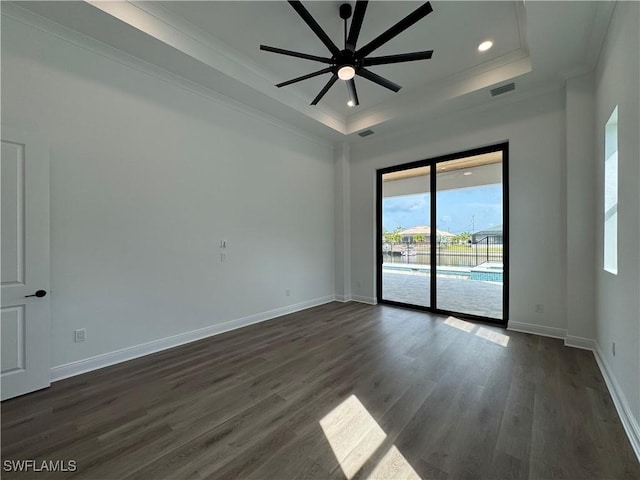 empty room featuring a raised ceiling, crown molding, ceiling fan, and baseboards