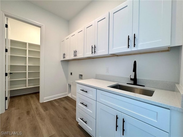 washroom with dark wood-type flooring, hookup for an electric dryer, a sink, baseboards, and cabinet space