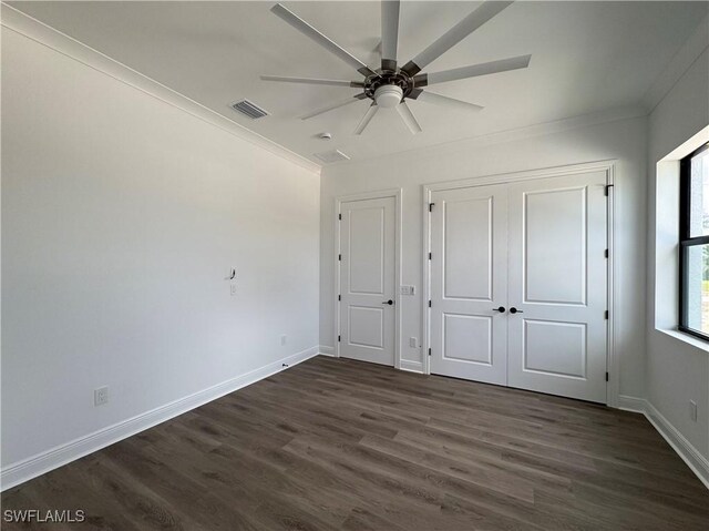 unfurnished bedroom featuring crown molding, ceiling fan, visible vents, baseboards, and dark wood-style floors