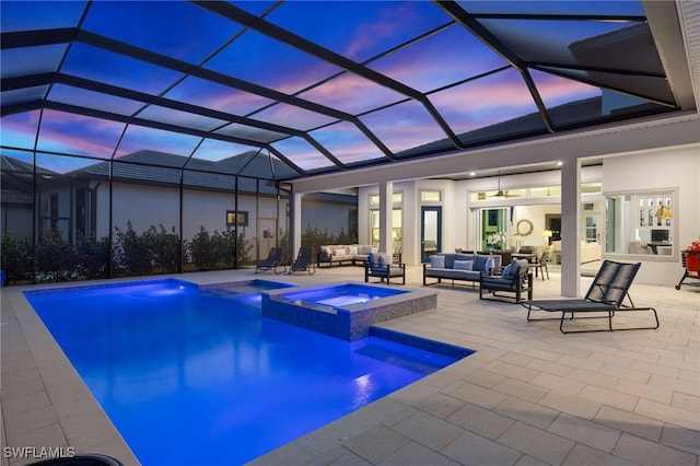 pool at dusk featuring outdoor lounge area, a patio area, a pool with connected hot tub, and a ceiling fan