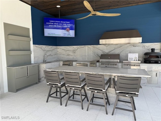 kitchen with wooden ceiling, ceiling fan, light stone countertops, and wall chimney exhaust hood