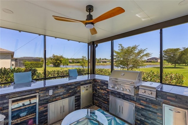 view of patio featuring area for grilling, grilling area, a water view, and a ceiling fan