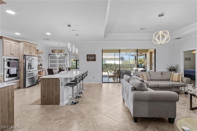 living room with visible vents, crown molding, a raised ceiling, and an inviting chandelier
