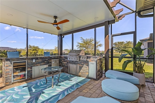 sunroom / solarium featuring exterior kitchen, ceiling fan, and a healthy amount of sunlight