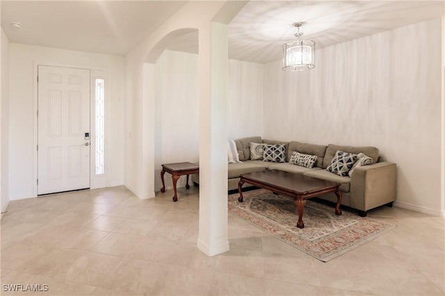 living room with arched walkways, baseboards, and light tile patterned flooring