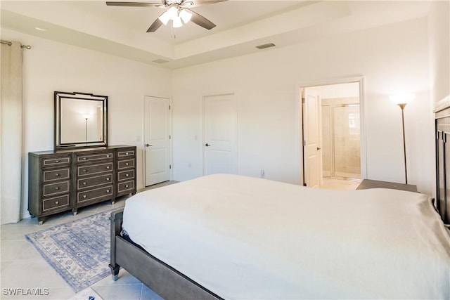 bedroom with visible vents, a ceiling fan, ensuite bath, a tray ceiling, and light tile patterned floors