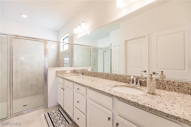bathroom featuring a stall shower, double vanity, a sink, and tile patterned floors