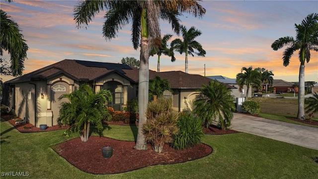 24342 Saragossa Ln, Punta Gorda, FL 33955 - view of front of home with driveway, a front yard, stucco siding, roof mounted solar panels, and a garage