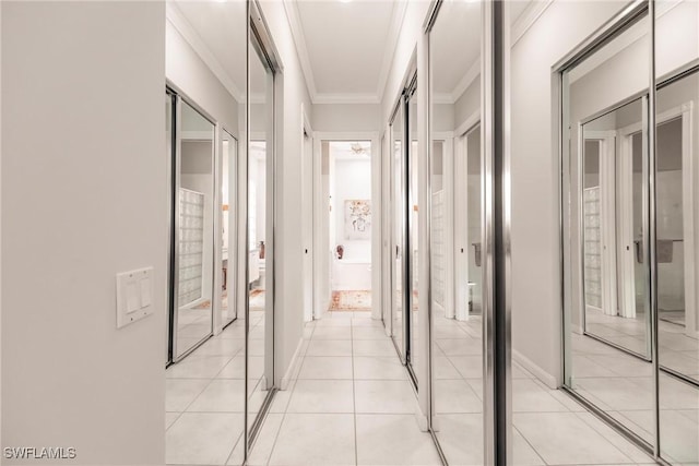 hallway featuring light tile patterned flooring, crown molding, and baseboards