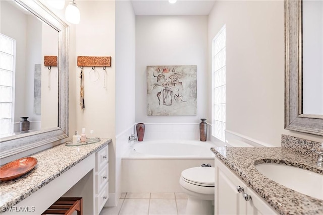 full bathroom featuring two vanities, a garden tub, toilet, and a sink