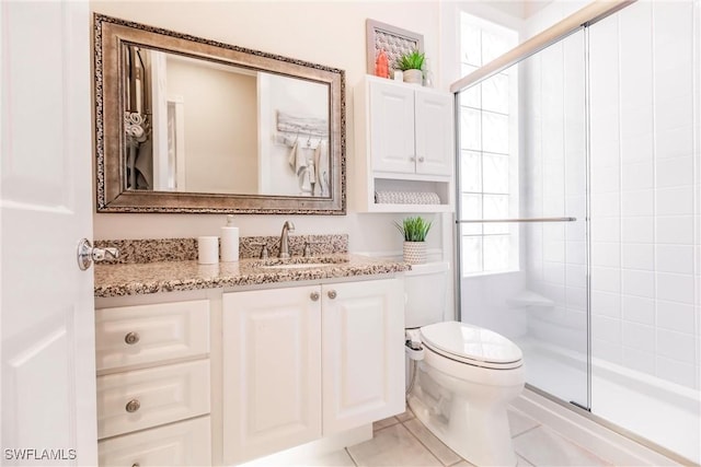 bathroom featuring toilet, vanity, tile patterned floors, and tiled shower