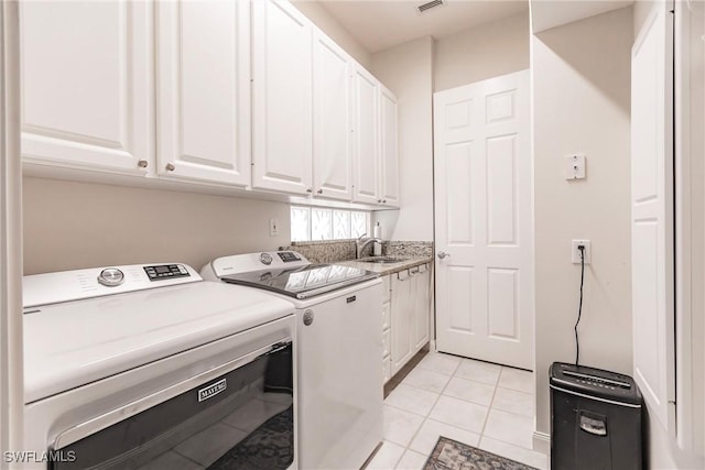 washroom with a sink, light tile patterned floors, cabinet space, visible vents, and independent washer and dryer