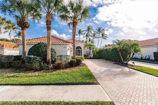 mediterranean / spanish house with a tile roof, stucco siding, and decorative driveway