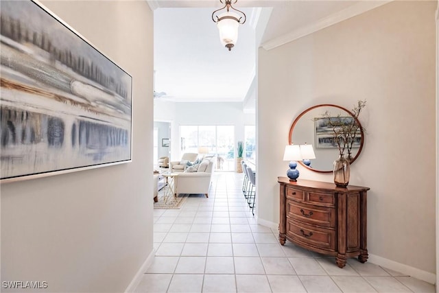 hall featuring baseboards, ornamental molding, and light tile patterned flooring