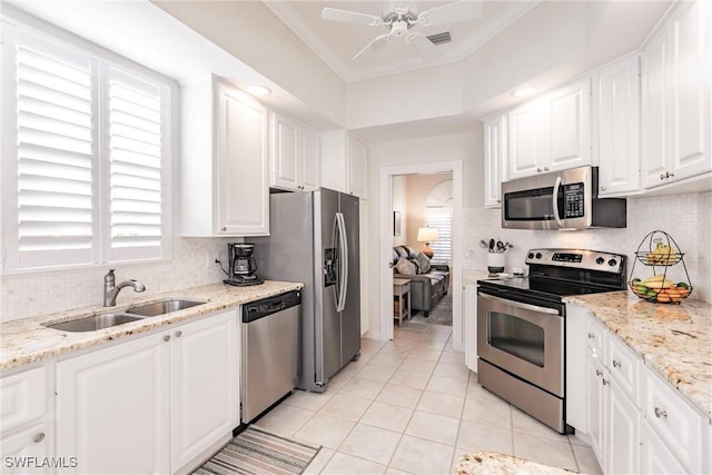 kitchen featuring a ceiling fan, a sink, light tile patterned floors, stainless steel appliances, and white cabinets