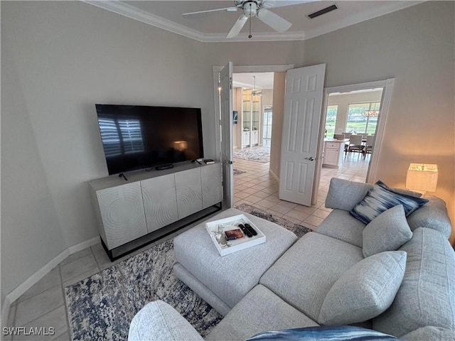 living area with light tile patterned flooring, baseboards, visible vents, a ceiling fan, and crown molding