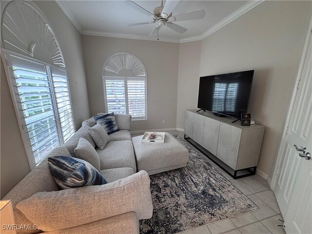 living area with light tile patterned floors, baseboards, ceiling fan, and crown molding