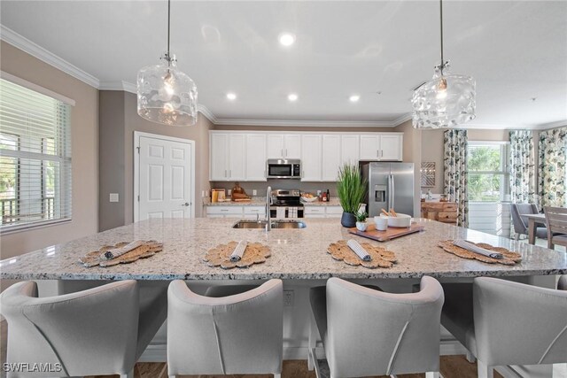 14600 Sycamore Ct Unit 2022, Punta Gorda, FL 33955 - kitchen featuring stainless steel appliances, ornamental molding, a large island, white cabinetry, and a sink