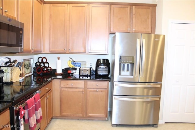 14768 Cranberry Ct, Naples, FL 34114 - kitchen featuring brown cabinetry, dark stone countertops, appliances with stainless steel finishes, and light tile patterned floors