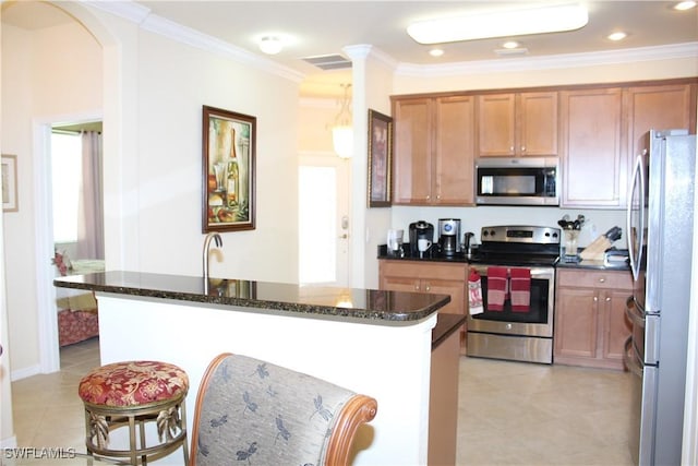 14768 Cranberry Ct, Naples, FL 34114 - kitchen with crown molding, light tile patterned floors, dark stone countertops, stainless steel appliances, and brown cabinets
