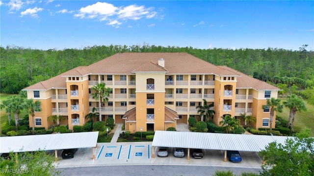 10520 Amiata Way Unit 104, Fort Myers, FL 33913 - view of apartment building / complex featuring covered and uncovered parking and a wooded view