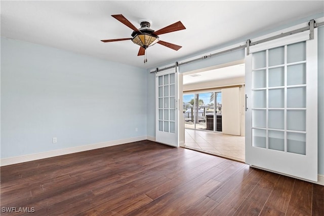2020 Aruba Ave, Fort Myers, FL 33905 - spare room featuring a barn door, wood finished floors, baseboards, and ceiling fan