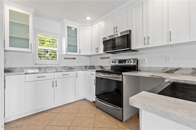 2020 Aruba Ave, Fort Myers, FL 33905 - kitchen featuring appliances with stainless steel finishes, white cabinetry, light tile patterned floors, light stone countertops, and glass insert cabinets
