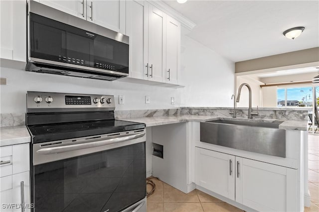 2020 Aruba Ave, Fort Myers, FL 33905 - kitchen featuring appliances with stainless steel finishes, a sink, white cabinetry, light tile patterned floors, and a peninsula