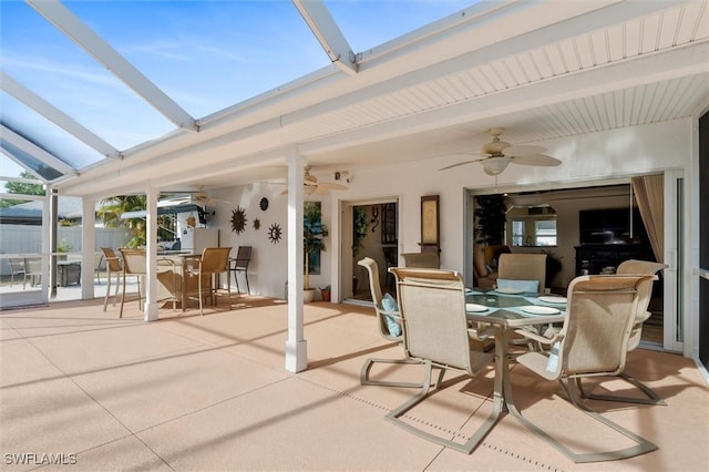 view of patio / terrace featuring outdoor dining area, a lanai, fence, and ceiling fan