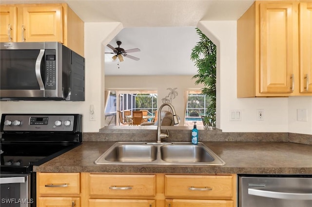 kitchen with stainless steel appliances, a sink, dark countertops, ceiling fan, and light brown cabinets