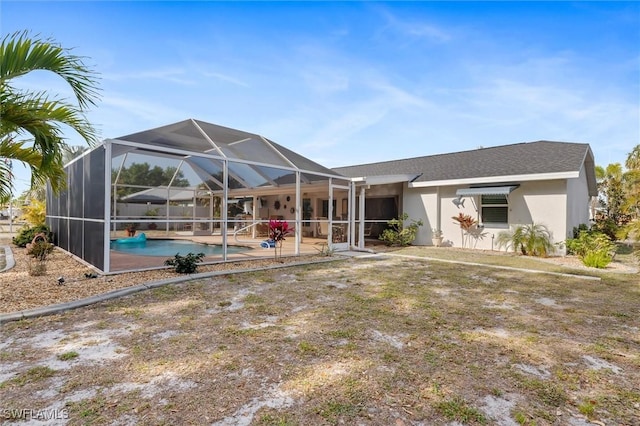 back of property featuring glass enclosure, an outdoor pool, stucco siding, and a patio