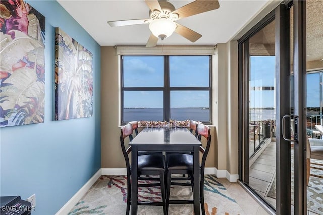 dining space with a ceiling fan, light tile patterned flooring, and baseboards