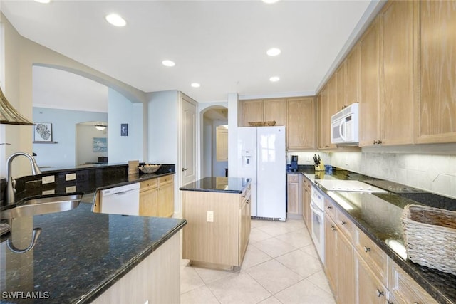 kitchen with white appliances, arched walkways, a sink, a center island, and light brown cabinetry