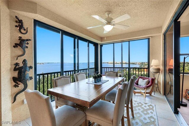 sunroom / solarium featuring a water view, a textured ceiling, and tile patterned flooring