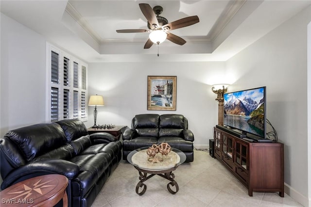 living room featuring a tray ceiling, baseboards, ceiling fan, and crown molding