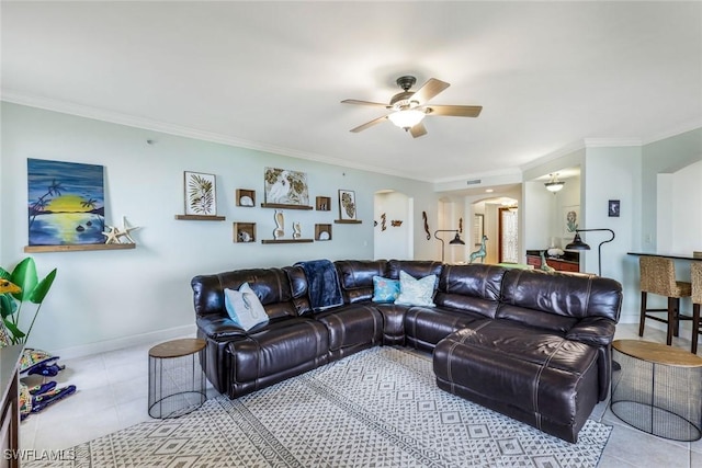 living area with arched walkways, ceiling fan, ornamental molding, and tile patterned flooring