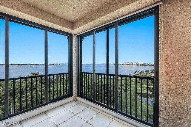 11600 Court Of Palms Unit 506, Fort Myers, FL 33908 - unfurnished sunroom featuring a water view, a textured wall, and tile patterned flooring
