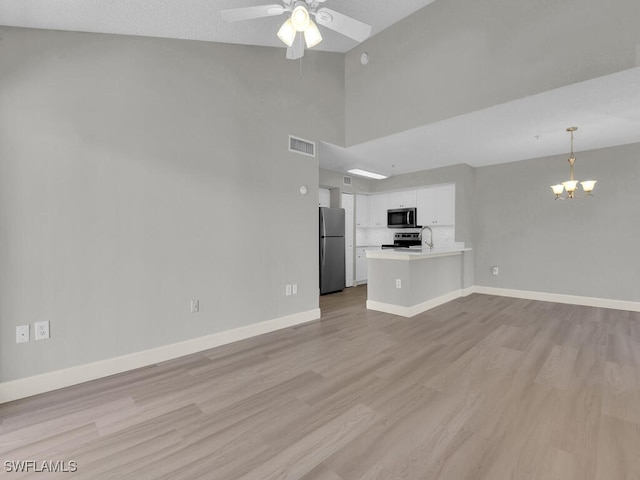 1180 Wildwood Lakes Blvd Unit 207, Naples, FL 34104 - unfurnished living room featuring baseboards, visible vents, high vaulted ceiling, light wood finished floors, and ceiling fan with notable chandelier
