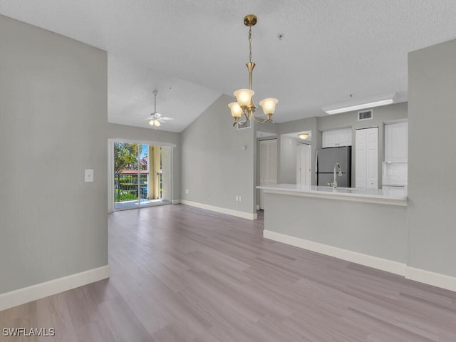 1180 Wildwood Lakes Blvd Unit 207, Naples, FL 34104 - unfurnished living room featuring baseboards, vaulted ceiling, visible vents, ceiling fan with notable chandelier, and wood finished floors
