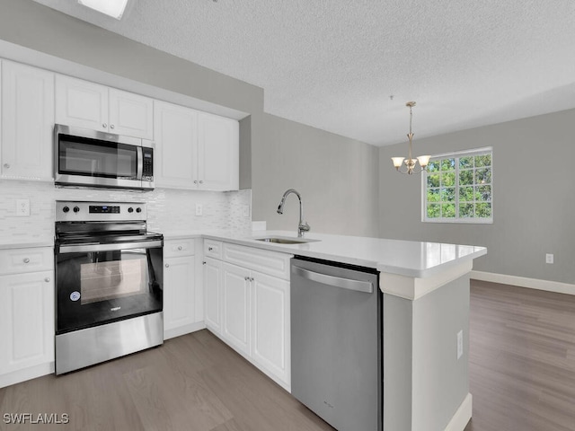 1180 Wildwood Lakes Blvd Unit 207, Naples, FL 34104 - kitchen with a sink, appliances with stainless steel finishes, wood finished floors, and a peninsula