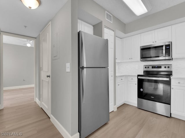1180 Wildwood Lakes Blvd Unit 207, Naples, FL 34104 - kitchen with visible vents, baseboards, light wood-style floors, white cabinetry, and stainless steel appliances