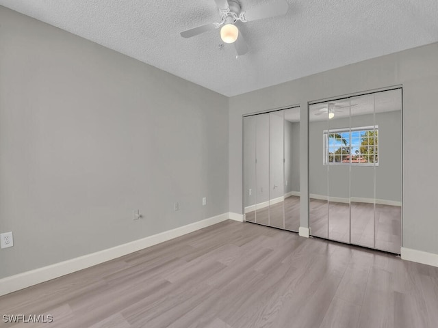 1180 Wildwood Lakes Blvd Unit 207, Naples, FL 34104 - unfurnished bedroom with baseboards, a textured ceiling, two closets, ceiling fan, and wood finished floors