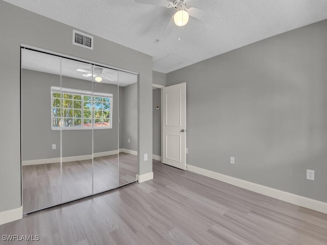 1180 Wildwood Lakes Blvd Unit 207, Naples, FL 34104 - unfurnished bedroom with visible vents, baseboards, a closet, a textured ceiling, and wood finished floors