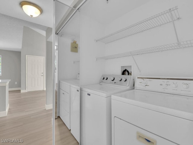 1180 Wildwood Lakes Blvd Unit 207, Naples, FL 34104 - clothes washing area featuring light wood-style flooring, washing machine and clothes dryer, laundry area, and baseboards