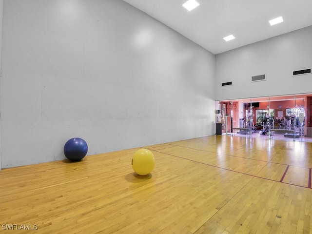 1180 Wildwood Lakes Blvd Unit 207, Naples, FL 34104 - workout room with hardwood / wood-style floors, a towering ceiling, and visible vents
